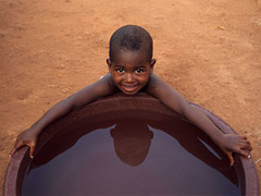 Boy at water tank, smiling.